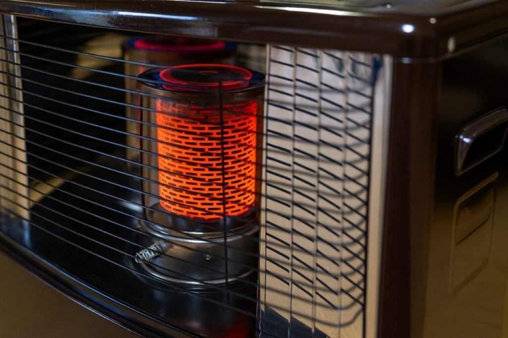 赤く燃える灯油ストーブの内部が見える室内の様子。安全カバー越しにやわらかな暖かさが伝わる構図。