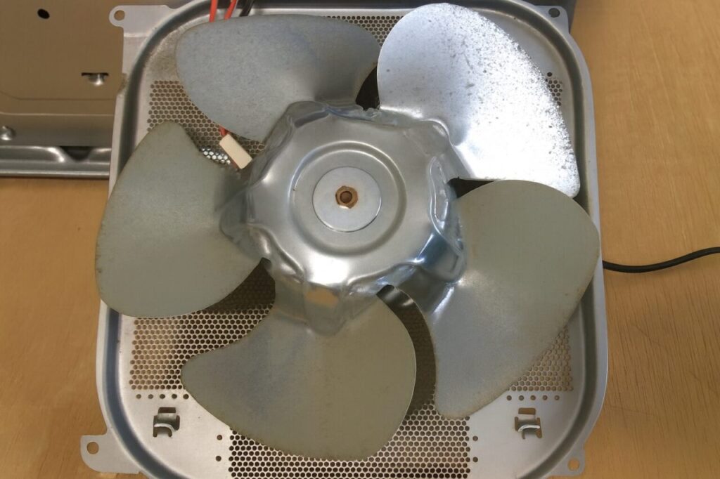換気扇の内部にある金属製ファンを上から見た構図で、4枚羽根に汚れや経年劣化が見られる状態を写した様子