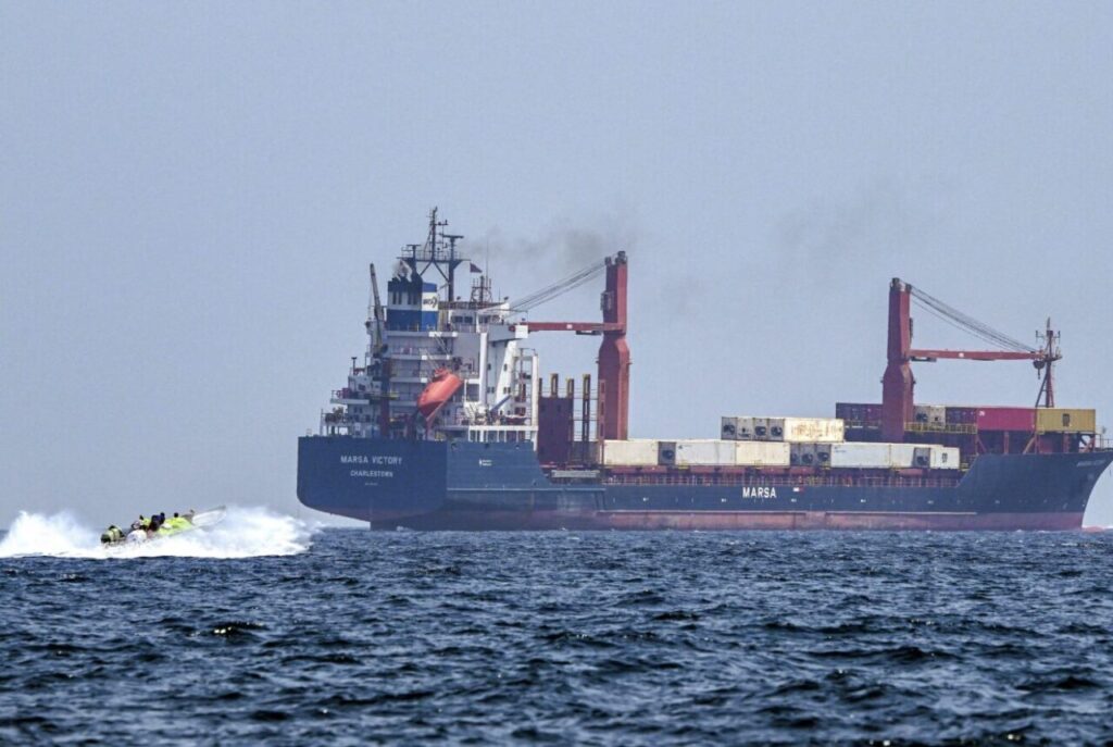 貨物船の近くを高速で走る小型ボートが接近している海上の様子