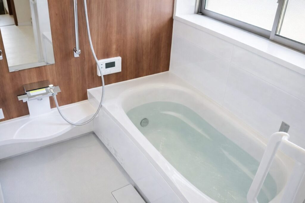 浴槽に水が張られた明るいユニットバスの内観とシャワー設備