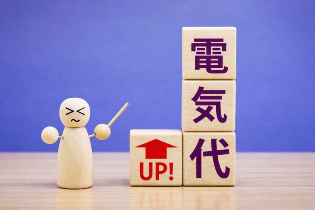 電気代の値上がりを示す木製ブロックと、不満そうに指し示す人形のイメージ