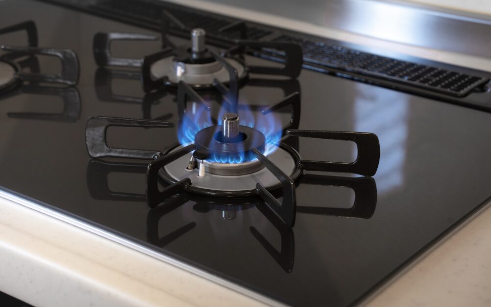黒いガラストップコンロで青い炎が安定して燃えているガスバーナーの様子