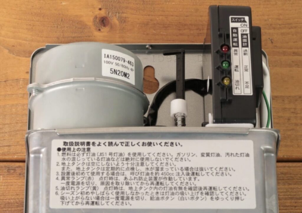 オイルサーバー内部の実機写真。モーターや油面検知用フロート、運転ランプを備え、灯油を自動で補給する仕組みが確認できる。