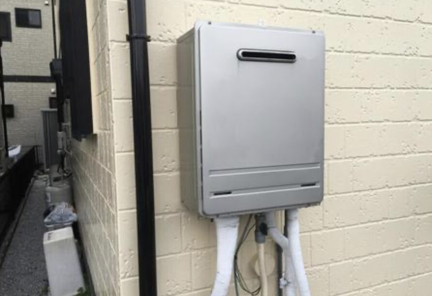 住宅の外壁に設置された屋外用ガス給湯器本体と、下部から配管が立ち上がっている設置状況の様子