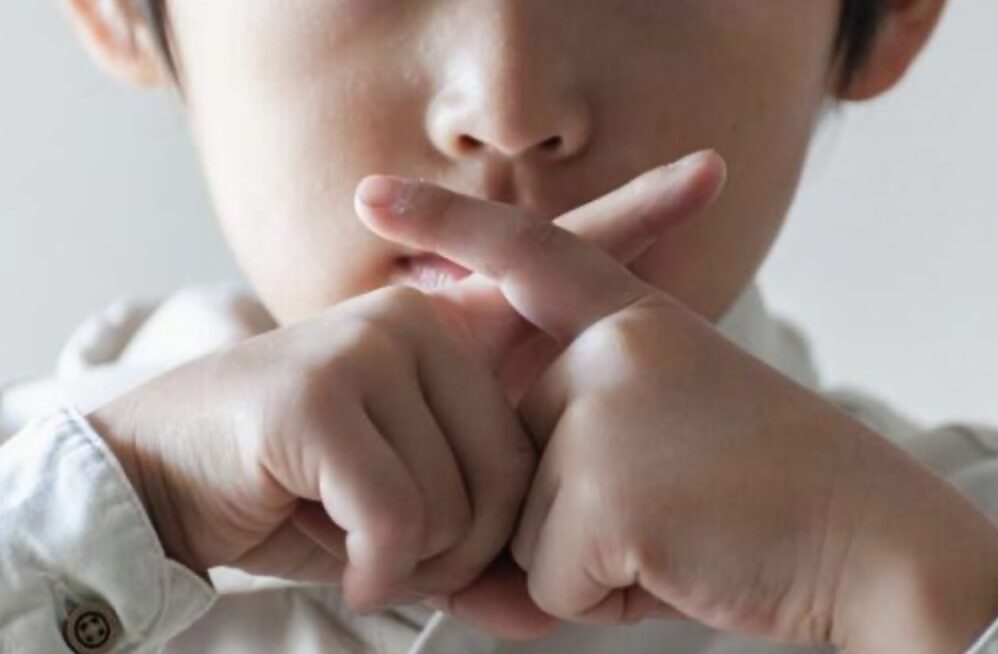 小さな子供が指でばつ印を作っている様子