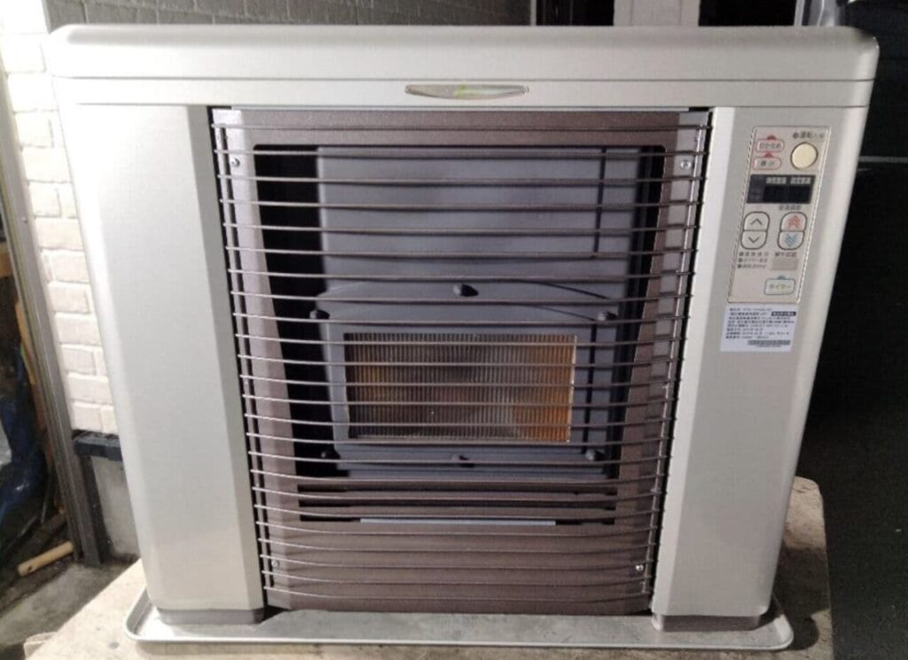 室内に設置された据置型のFF式石油ストーブを正面から撮影した様子で、前面ガード越しに燃焼部と操作パネルが確認できる状態