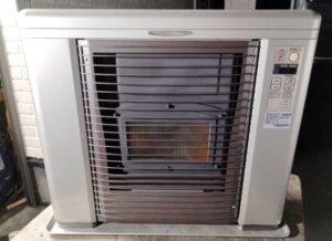 室内に設置された据置型のFF式石油ストーブを正面から撮影した様子で、前面ガード越しに燃焼部と操作パネルが確認できる状態