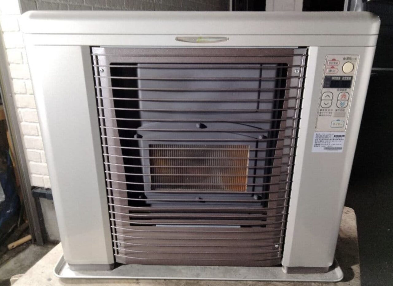 室内に設置された据置型のFF式石油ストーブを正面から撮影した様子で、前面ガード越しに燃焼部と操作パネルが確認できる状態