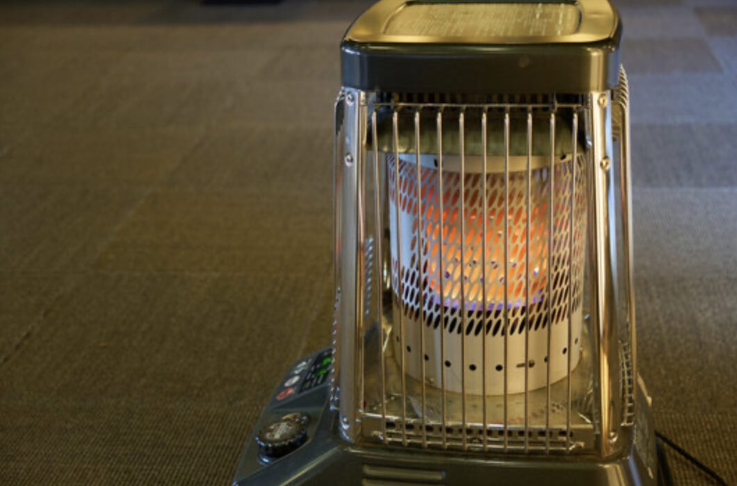 石油ストーブ内部で赤く発光する燃焼筒をガード越しに撮影した写真