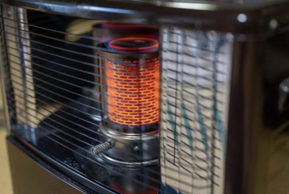 石油ストーブ内部で赤く発光する燃焼筒をガード越しに撮影した写真