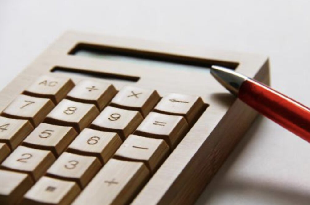 計算機の上にペンを置き、費用や金額を計算している場面