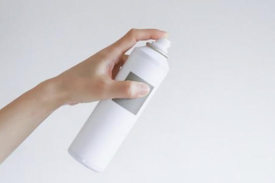 白い消臭スプレーを手に持ち、噴射しようとしている様子