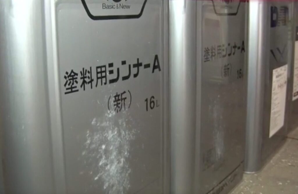 塗料用シンナーの金属缶が複数並び、表面に白い粉や汚れが付着している様子を写した画像