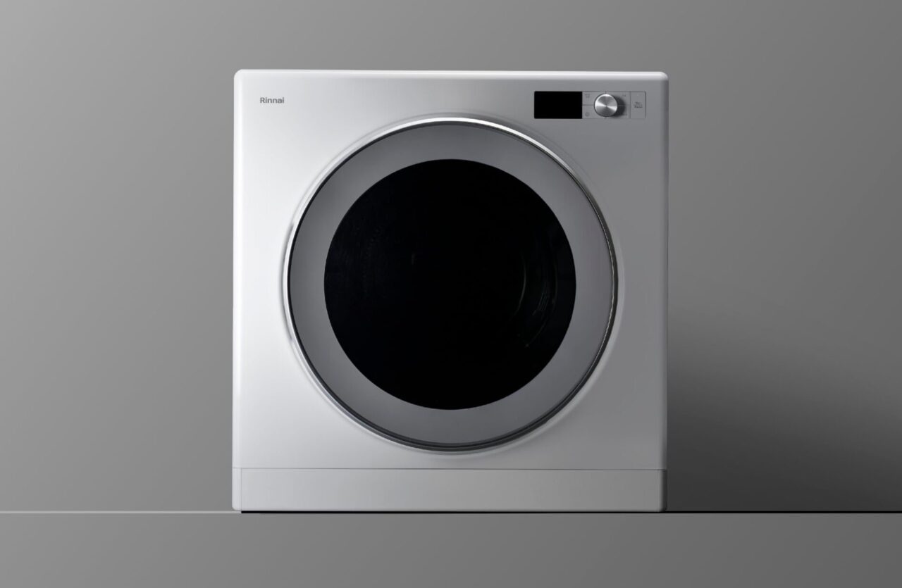 白を基調としたドラム式衣類乾燥機の本体を正面から撮影したシンプルなイメージ。大きな円形ドアと操作パネルを備え、乾燥機のデザインや外観が分かる構図